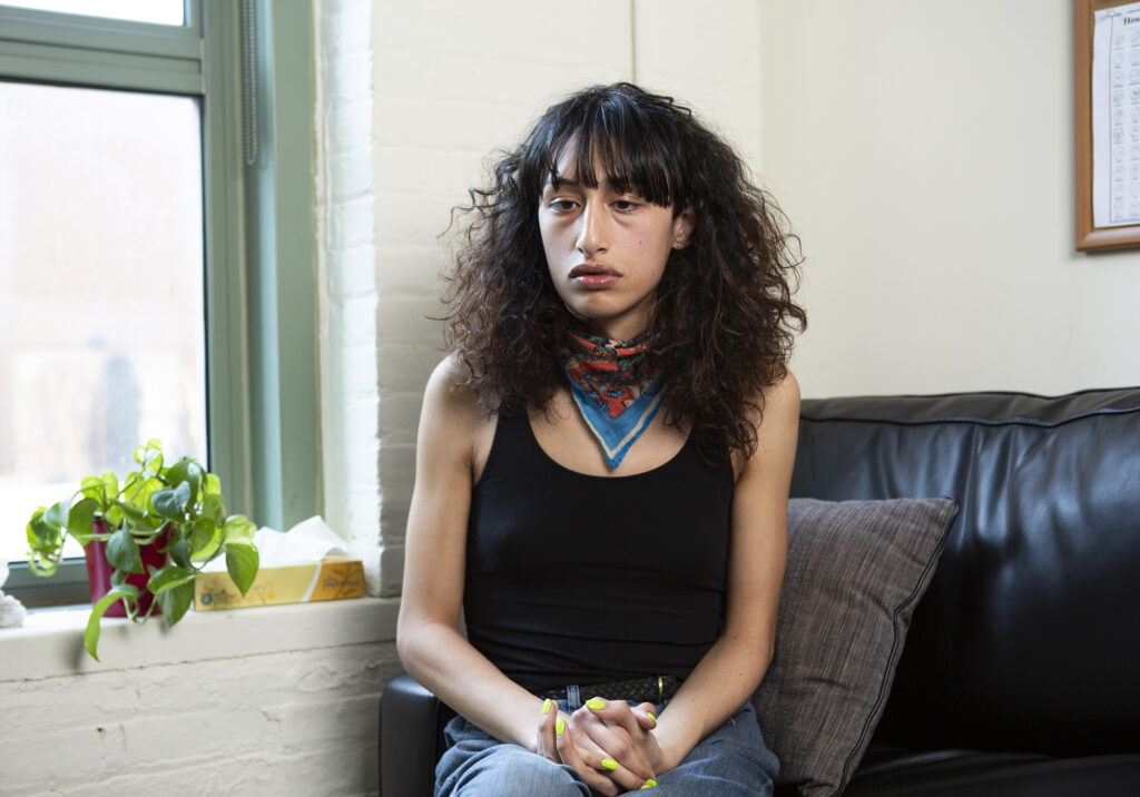A trans woman sitting on a therapist couch and looking upset