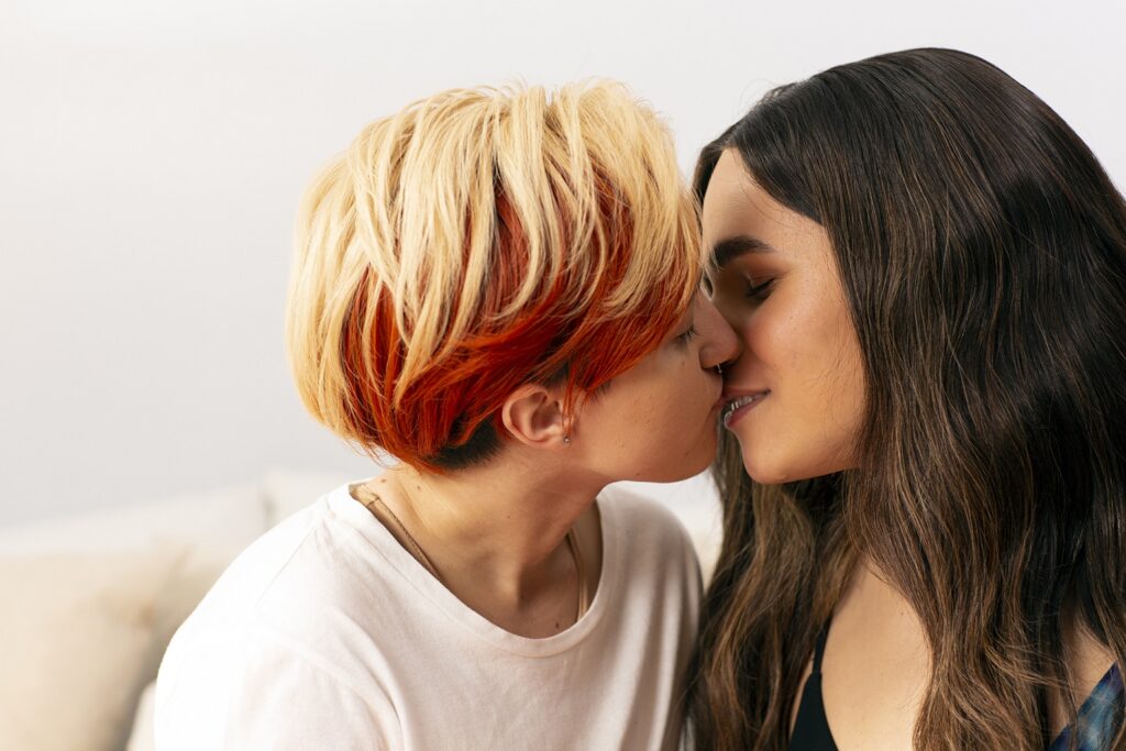 Transmasculine gender nonconforming person kissing female partner